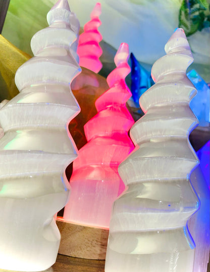 Spirale de sélénite éclairée en rose parmi des spirales blanches