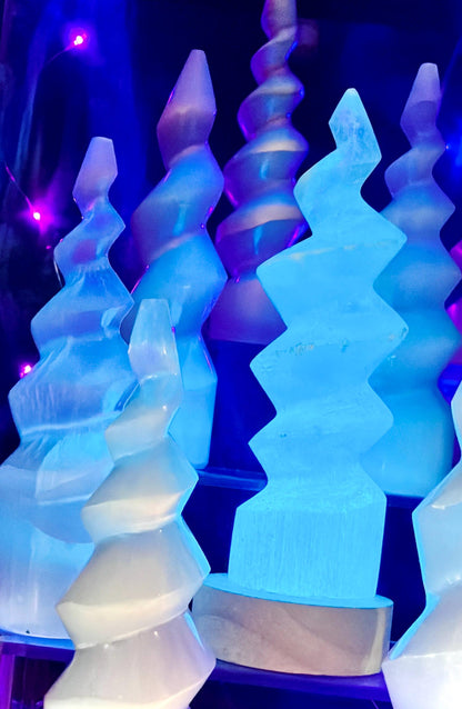 Plusieurs lampes en spirale de sélénite éclairées en bleu sur des socles en bois