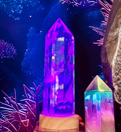 Grande pointe de verre éclairée en violet sur un socle en bois, dans un décor bleu