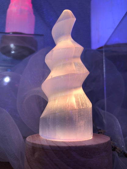 Lampe en spirale de sélénite éclairée en blanc chaud sur un socle en bois