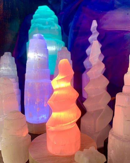 Spirale de sélénite éclairée en orange et jaune parmi d’autres lampes de la boutique