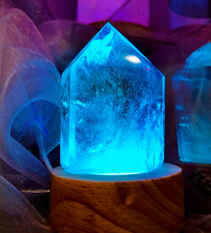 Pointe en cristal de roche craquelé éclairée en bleu turquoise sur son socle en bois