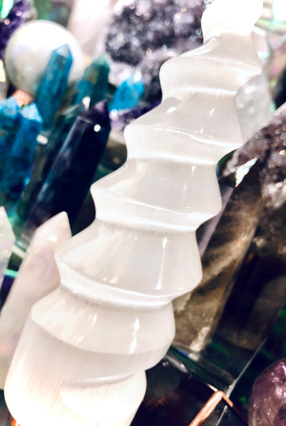 Gros plan sur une spirale blanche de sélénite tenue dans une main